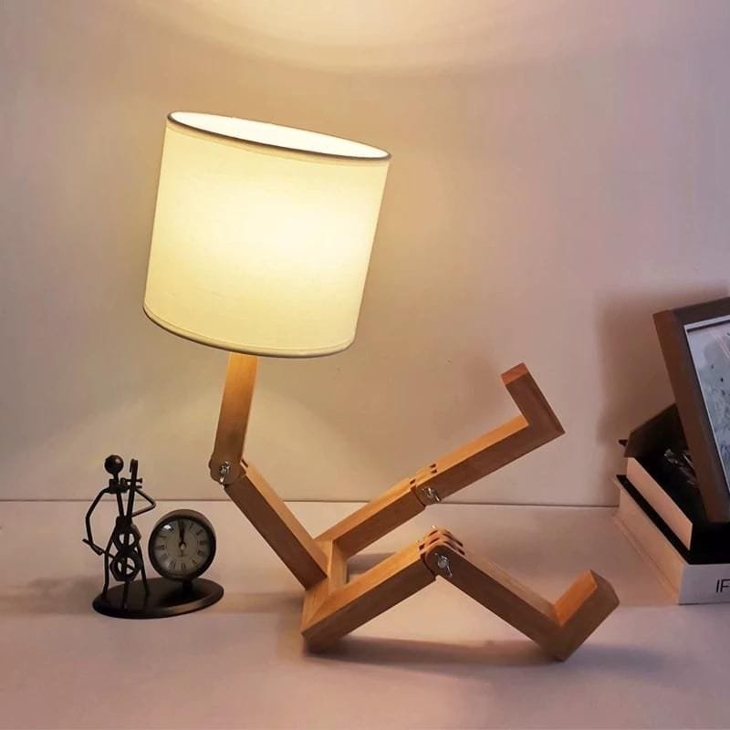 lampe de chevet bonhomme en bois allumée sur un meuble