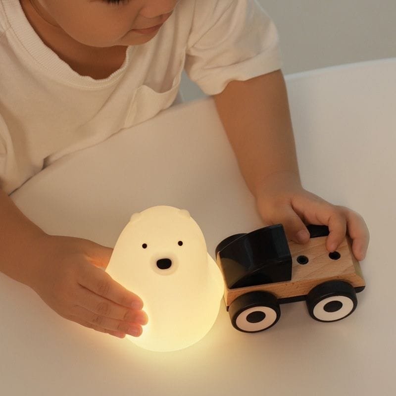 Veilleuse Ourson : Douce Lumière pour Apaiser les Terreurs Nocturnes 1 Enfant qui joue avec la veilleuse ourson allumée
